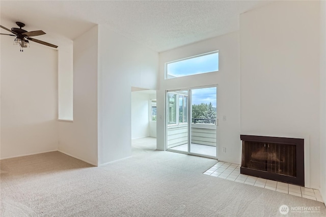 7435 Old Redmond Rd Unit 325, Redmond, WA 98052 - unfurnished living room featuring carpet floors, a towering ceiling, a ceiling fan, and a fireplace with flush hearth