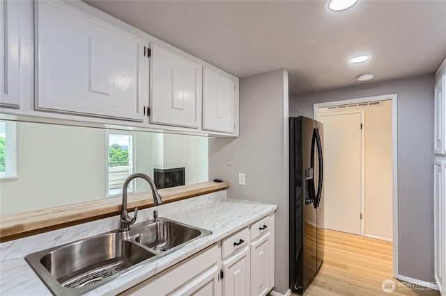 7435 Old Redmond Rd Unit 325, Redmond, WA 98052 - kitchen with black refrigerator with ice dispenser, white cabinets, recessed lighting, light wood finished floors, and light stone counters