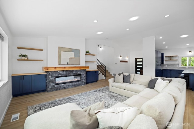 2403 E Hemmi Rd, Bellingham, WA 98226 - living area featuring light wood-style floors, a stone fireplace, recessed lighting, lofted ceiling, and stairs