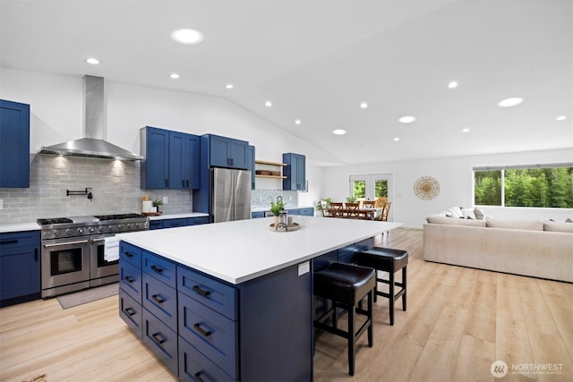 2403 E Hemmi Rd, Bellingham, WA 98226 - kitchen with appliances with stainless steel finishes, wall chimney range hood, blue cabinets, a breakfast bar, and a center island