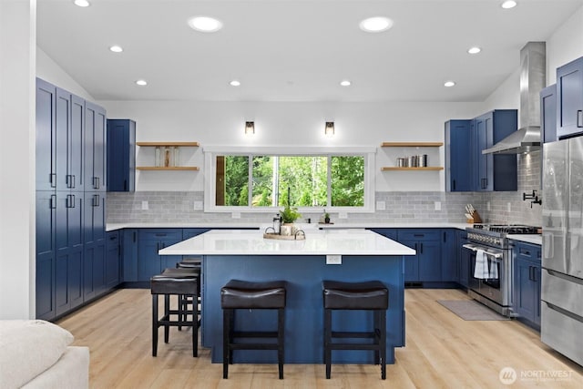 2403 E Hemmi Rd, Bellingham, WA 98226 - kitchen with open shelves, stainless steel appliances, wall chimney exhaust hood, blue cabinetry, and recessed lighting