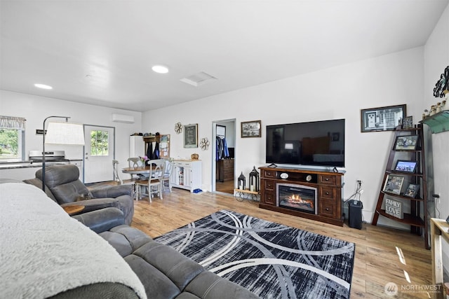 2403 E Hemmi Rd, Bellingham, WA 98226 - living area featuring wood finished floors, recessed lighting, a glass covered fireplace, and an AC wall unit