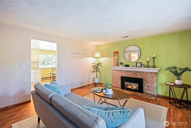 5428 172nd St SW, Lynnwood, WA 98037 - living room featuring a baseboard radiator, wood finished floors, a brick fireplace, and a textured ceiling