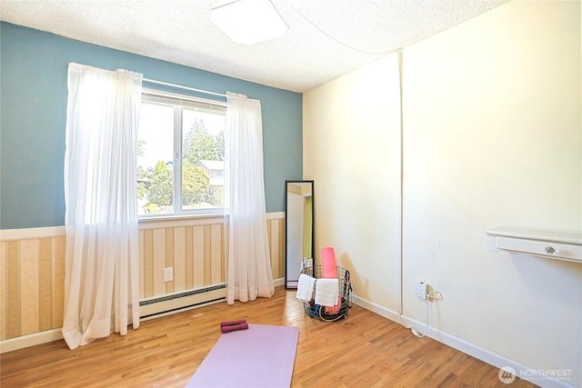 5428 172nd St SW, Lynnwood, WA 98037 - workout area featuring a baseboard heating unit, wood finished floors, and a textured ceiling