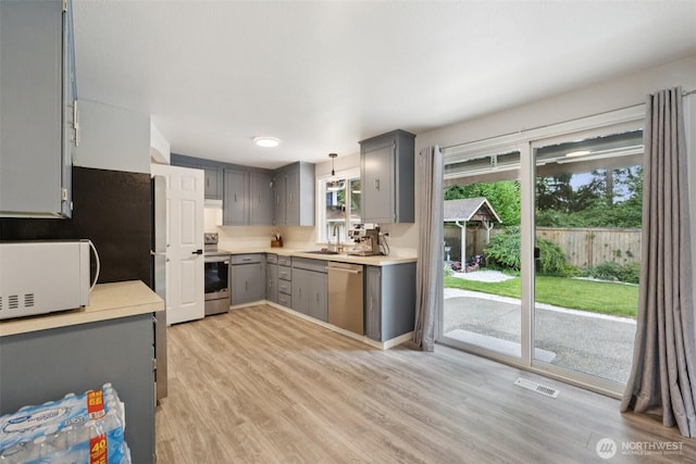 5502 82nd Street Ct E, Puyallup, WA 98371 - kitchen featuring appliances with stainless steel finishes, gray cabinets, light countertops, light wood-type flooring, and decorative light fixtures
