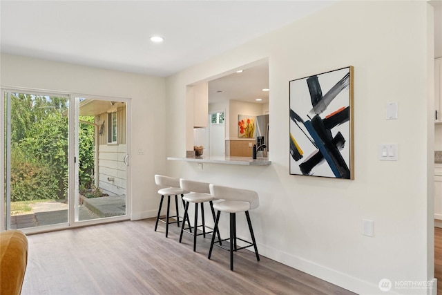 22720 90th Ave W, Edmonds, WA 98026 - kitchen featuring stainless steel fridge, a breakfast bar, wood finished floors, recessed lighting, and light countertops