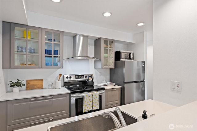 1926 Fairview Ave E Unit 307, Seattle, WA 98102 - kitchen with stainless steel appliances, wall chimney exhaust hood, gray cabinetry, glass insert cabinets, and light countertops