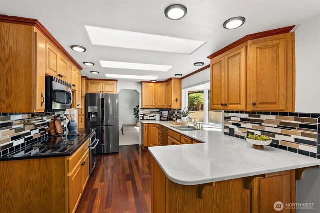 3322 Pacific Way, Longview, WA 98632 - kitchen featuring stainless steel appliances, a peninsula, a skylight, decorative backsplash, and dark wood-type flooring
