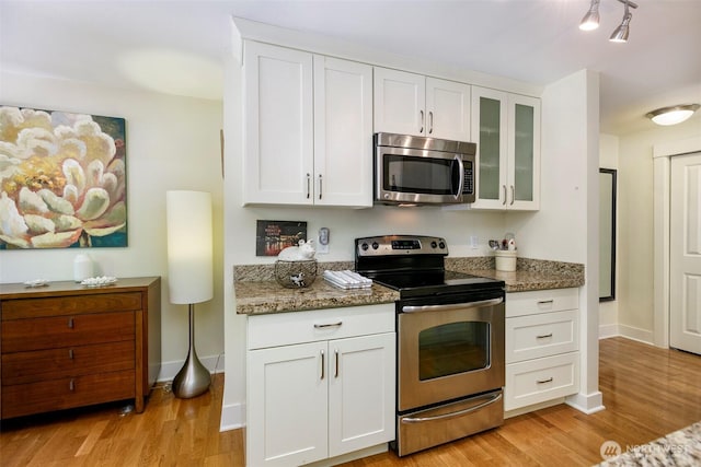 22910 90th Ave W Unit C103, Edmonds, WA 98026 - kitchen with appliances with stainless steel finishes, glass insert cabinets, white cabinets, and light wood-style flooring
