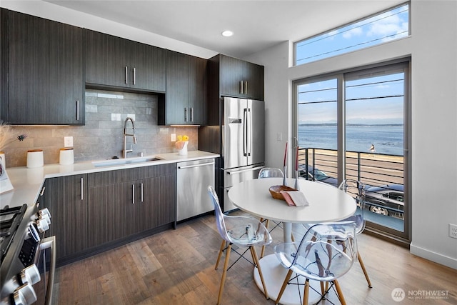 1706 Alki Ave SW Unit A, Seattle, WA 98116 - kitchen featuring stainless steel appliances, light countertops, decorative backsplash, wood finished floors, and a water view