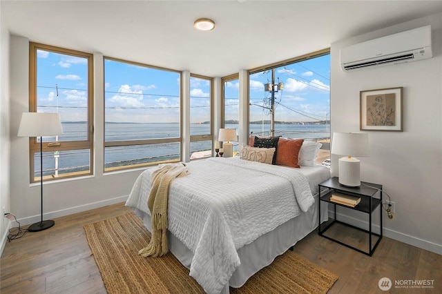 1706 Alki Ave SW Unit A, Seattle, WA 98116 - bedroom featuring a wall unit AC, a water view, multiple windows, and wood finished floors