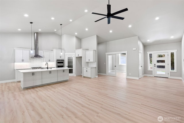 821 174th Ave NW, Lakebay, WA 98349 - kitchen featuring high vaulted ceiling, wall chimney range hood, appliances with stainless steel finishes, a spacious island, and open floor plan