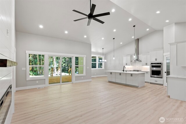 821 174th Ave NW, Lakebay, WA 98349 - kitchen with a large fireplace, open floor plan, wall chimney range hood, high vaulted ceiling, and light countertops