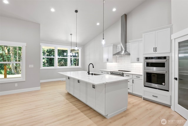 821 174th Ave NW, Lakebay, WA 98349 - kitchen featuring wall chimney exhaust hood, stainless steel appliances, decorative backsplash, light stone countertops, and light wood finished floors