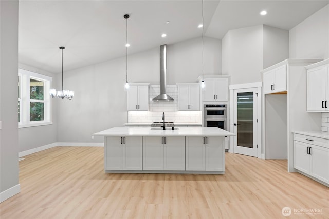 821 174th Ave NW, Lakebay, WA 98349 - kitchen featuring decorative backsplash, light wood-style floors, light countertops, wall chimney exhaust hood, and stainless steel double oven