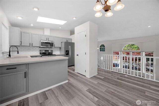 8618 217th Pl NE, Arlington, WA 98223 - kitchen featuring appliances with stainless steel finishes, a skylight, gray cabinets, tasteful backsplash, and light countertops