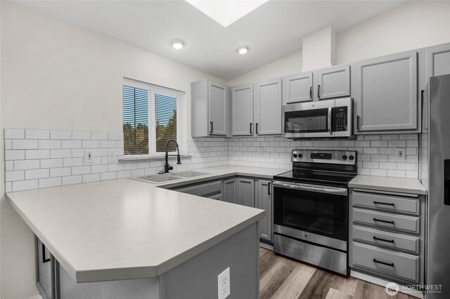 8618 217th Pl NE, Arlington, WA 98223 - kitchen with stainless steel appliances, gray cabinets, a peninsula, vaulted ceiling, and light countertops