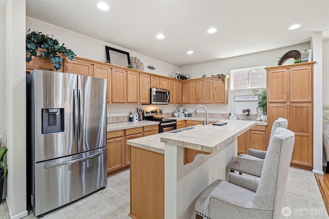 4318 3rd Ave NW, Olympia, WA 98502 - kitchen featuring appliances with stainless steel finishes, a kitchen island with sink, a breakfast bar, recessed lighting, and light tile patterned flooring