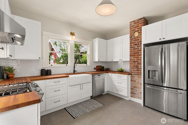 109 E Roanoke St, Seattle, WA 98102 - kitchen with butcher block countertops, stainless steel appliances, wall chimney exhaust hood, decorative backsplash, and white cabinetry