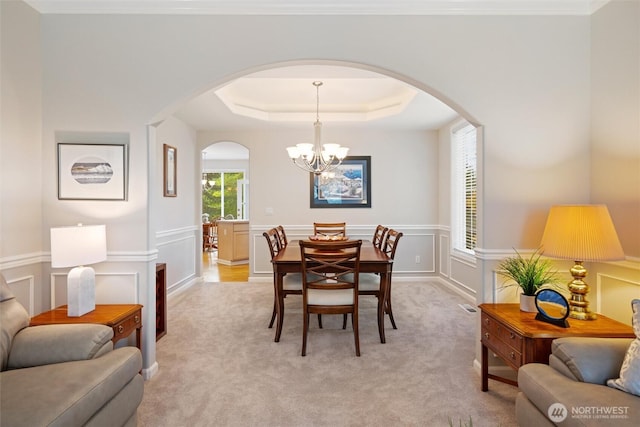 1402 Langara Cir, Bellingham, WA 98229 - dining space with arched walkways, a chandelier, light carpet, a tray ceiling, and a wainscoted wall
