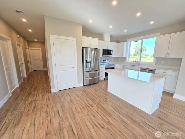 71 Falconcrest Ct, Sequim, WA 98382 - kitchen featuring stainless steel appliances, light countertops, white cabinets, light wood-style floors, and a kitchen island