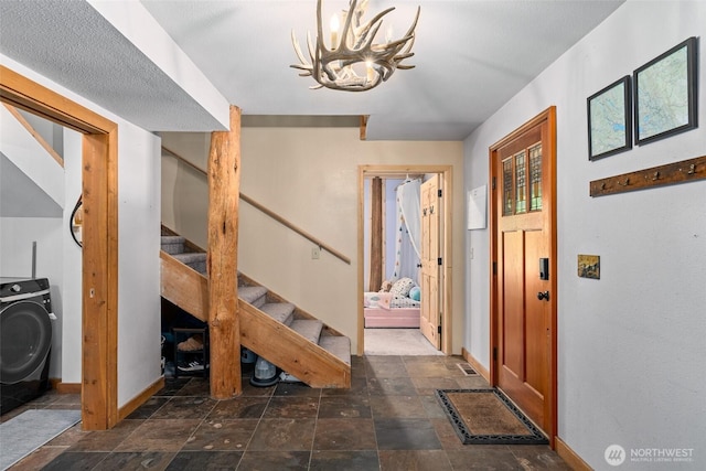 16845 Second Creek Rd, Leavenworth, WA 98826 - foyer entrance featuring stairway, washer / clothes dryer, a chandelier, and stone finish flooring