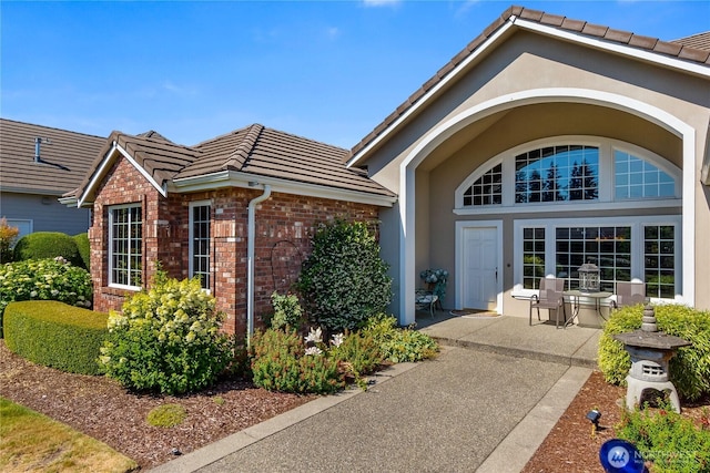 3912 Prestwick Ln SE, Olympia, WA 98501 - view of exterior entry with a tile roof, brick siding, and stucco siding