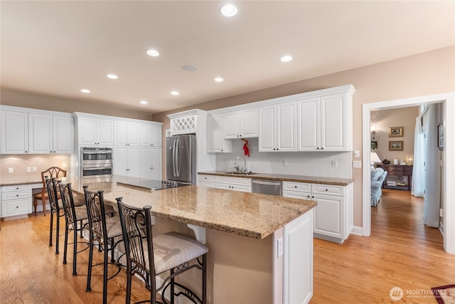 3912 Prestwick Ln SE, Olympia, WA 98501 - kitchen featuring appliances with stainless steel finishes, white cabinets, a kitchen breakfast bar, recessed lighting, and light wood finished floors