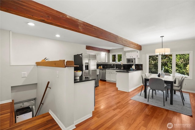 118 NW 132nd St, Seattle, WA 98177 - kitchen featuring stainless steel appliances, light wood-style flooring, dark countertops, white cabinetry, and beam ceiling