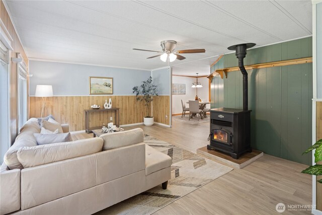 27114 320th Ave SE, Ravensdale, WA 98051 - living area with wood walls, a wood stove, ceiling fan, wood finished floors, and wainscoting