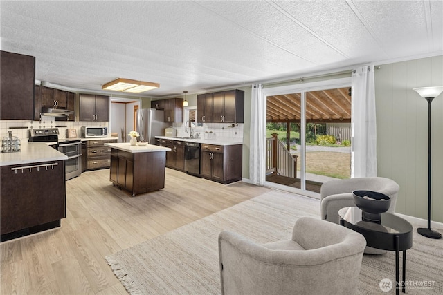 27114 320th Ave SE, Ravensdale, WA 98051 - kitchen featuring stainless steel appliances, under cabinet range hood, dark brown cabinetry, backsplash, and light countertops