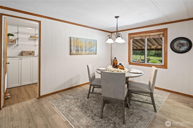 27114 320th Ave SE, Ravensdale, WA 98051 - dining area with crown molding, light wood-type flooring, a textured ceiling, and wood walls