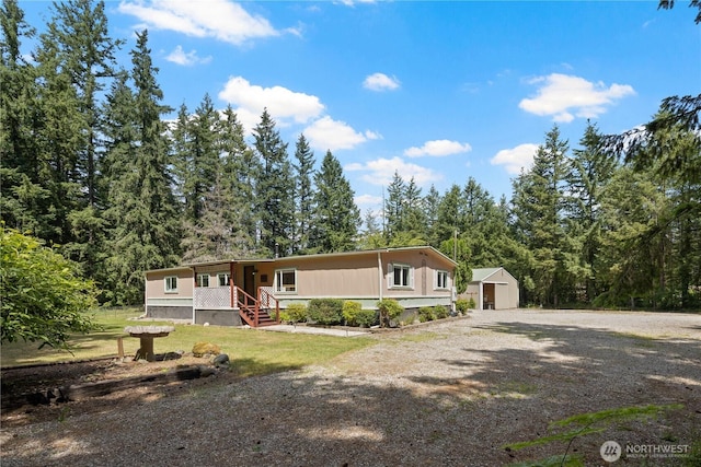 27114 320th Ave SE, Ravensdale, WA 98051 - manufactured / mobile home featuring a storage unit, a porch, driveway, and a wooded view