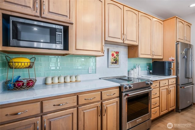 2401 Skyline Way Unit 203E, Anacortes, WA 98221 - kitchen with premium appliances, light wood-style floors, backsplash, light brown cabinets, and light stone counters