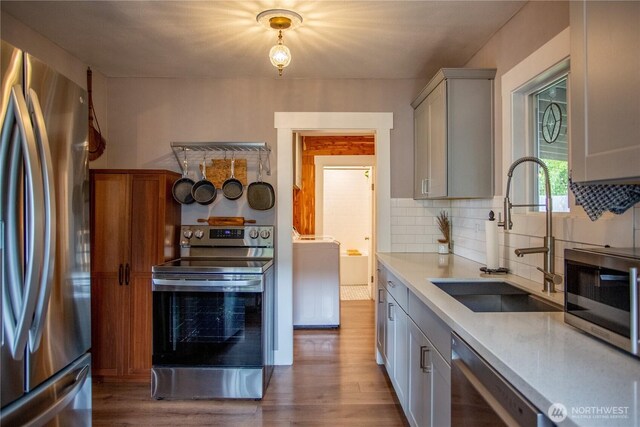 606 State St, Centralia, WA 98531 - kitchen featuring stainless steel appliances, washer / dryer, wood finished floors, light countertops, and tasteful backsplash