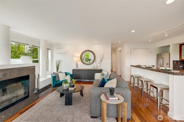 201 E Boston St Unit 2100, Seattle, WA 98102 - living area featuring wood finished floors, a wall mounted AC, a tile fireplace, track lighting, and recessed lighting