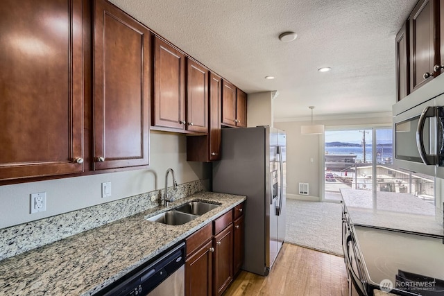 2514 57th Ave SW Unit 301, Seattle, WA 98116 - kitchen with stainless steel appliances, light wood-style floors, light stone countertops, ornamental molding, and a textured ceiling