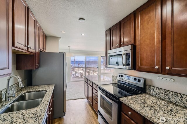 2514 57th Ave SW Unit 301, Seattle, WA 98116 - kitchen with stainless steel appliances, light wood-type flooring, light stone counters, recessed lighting, and a textured ceiling