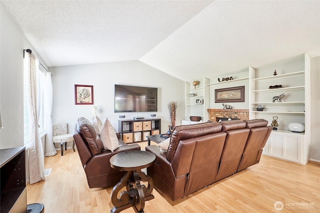 2003 SW 307th St Unit B, Federal Way, WA 98023 - living room with light wood-type flooring, vaulted ceiling, a textured ceiling, a fireplace, and built in shelves