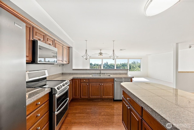 3201 Pacific Ave Unit 602, Tacoma, WA 98418 - kitchen with stainless steel appliances, brown cabinetry, a ceiling fan, dark wood-style flooring, and a peninsula