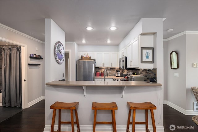 960 Harris Ave Unit 305, Bellingham, WA 98225 - kitchen featuring freestanding refrigerator, backsplash, dark wood-style floors, white cabinets, and a peninsula