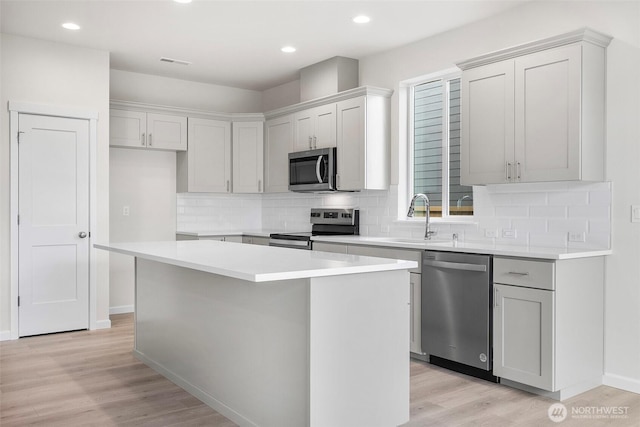 14756 88th Way SE Unit 10, Yelm, WA 98597 - kitchen with appliances with stainless steel finishes, a center island, light wood finished floors, tasteful backsplash, and light countertops