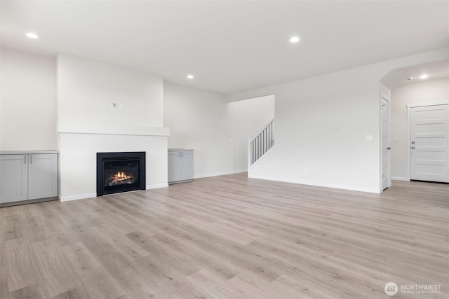 14756 88th Way SE Unit 10, Yelm, WA 98597 - unfurnished living room with light wood-style flooring, recessed lighting, a glass covered fireplace, and stairs