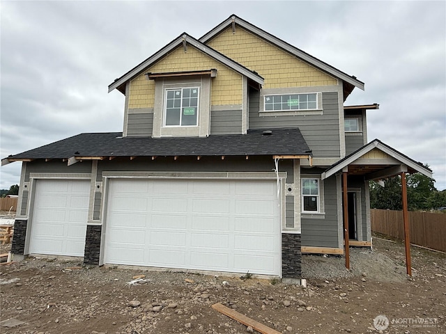 14756 88th Way SE Unit 10, Yelm, WA 98597 - view of front of home featuring stone siding, driveway, a shingled roof, and a garage