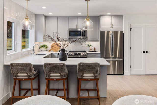 2616 E Roy St, Seattle, WA 98112 - kitchen with appliances with stainless steel finishes, gray cabinetry, light countertops, tasteful backsplash, and decorative light fixtures