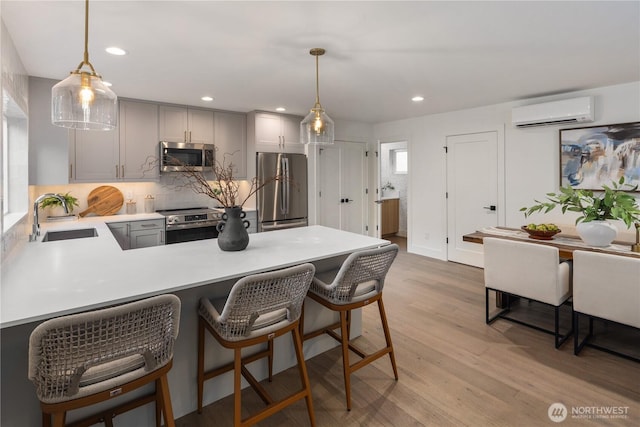 2616 E Roy St, Seattle, WA 98112 - kitchen with stainless steel appliances, a wall mounted AC, a peninsula, light countertops, and tasteful backsplash