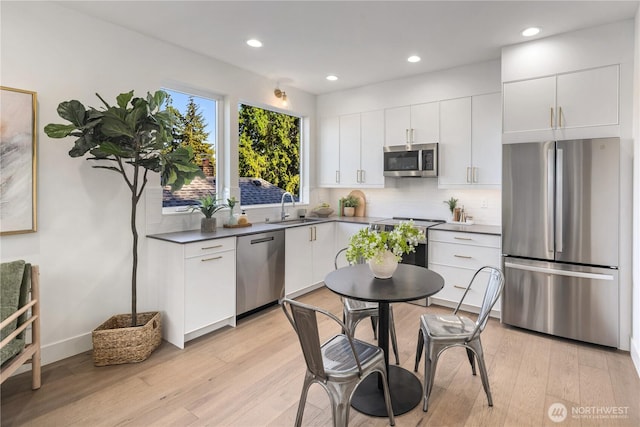 2618A E Roy St, Seattle, WA 98112 - kitchen featuring appliances with stainless steel finishes, decorative backsplash, light wood finished floors, and recessed lighting