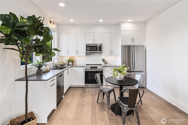 2618A E Roy St, Seattle, WA 98112 - kitchen with appliances with stainless steel finishes, light wood-style floors, white cabinets, tasteful backsplash, and recessed lighting
