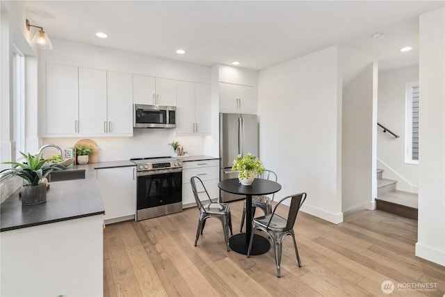 2618A E Roy St, Seattle, WA 98112 - kitchen with appliances with stainless steel finishes, light wood-style flooring, white cabinets, decorative backsplash, and recessed lighting