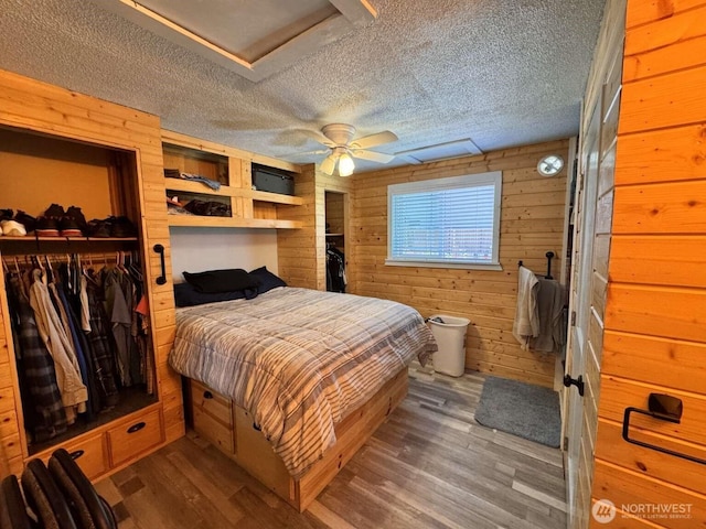 8839 Daffodil Ln SE, Olympia, WA 98513 - bedroom featuring wooden walls, a textured ceiling, wood finished floors, a closet, and a ceiling fan